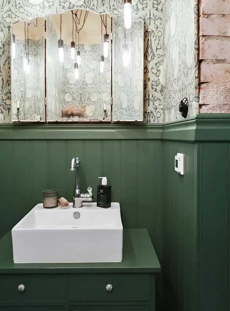 un espace avec un lambris vert et un lavabo en porcelaine