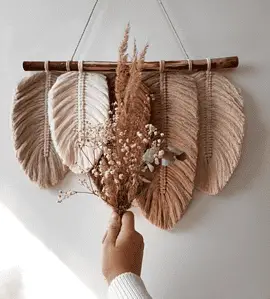 Vue sur une déco murale DIY avec une main de femme tenant un petit bouquet de fleurs