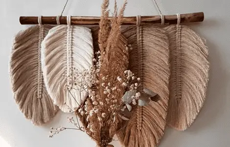 Vue sur une déco murale DIY avec une main de femme tenant un petit bouquet de fleurs