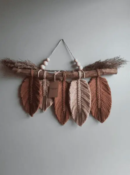 Une tenture avec des plumes en macramé marron et rose