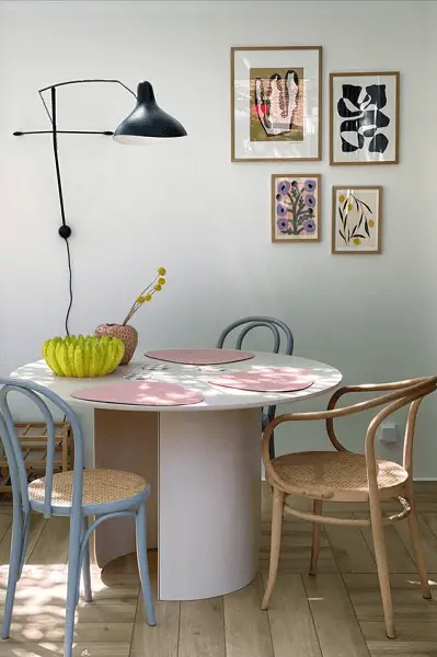 Des chaises bleu ciel et une chaise en bois clair autour d'une table rose pâle