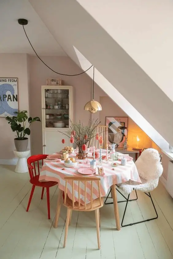 Une petite table ronde avec des chaises en bois brut, une chaise en métal et une chaise customisée avec de la peinture rouge