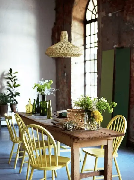 Des chaises en bois jaune citron autour d'une table de ferme dans un décor industriel et champêtre