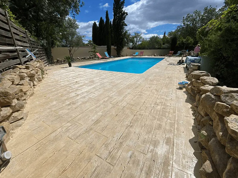 Inspiration parquet pour cette terrasse en bord de piscine imitation bois, réalisée en béton imprimé