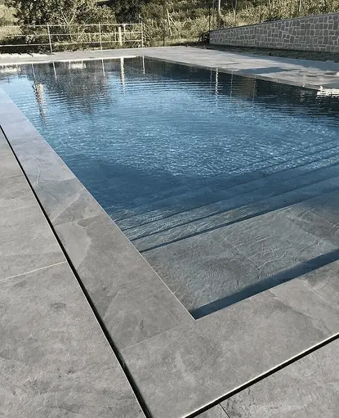 Une piscine enterrée au design très contemporain, avec un revêtement en béton empreinte dans des teintes grises