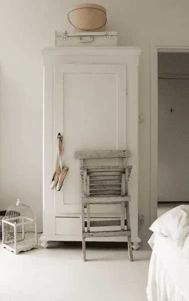 Une armoire en bois blanche dans une chambre à coucher au décor romantique
