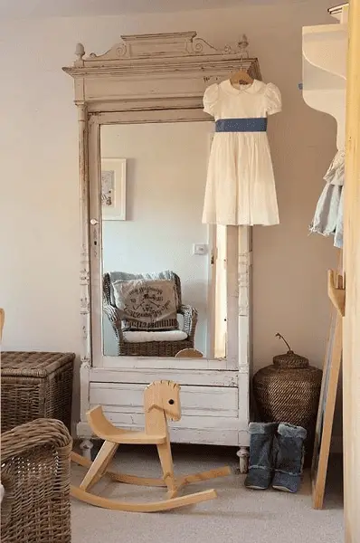 Une armoire en bois avec miroir dans une chambre de petite fille, rénovée dans un aspect vieilli pour s'harmoniser au décor