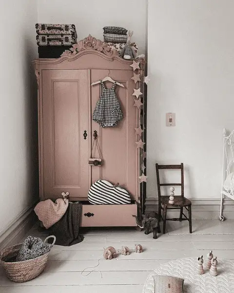 Une armoire rustique repeinte en rose dans une chambre de petite fille