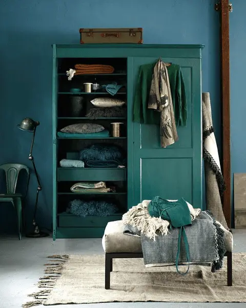 Une armoire en bois rénovée avec une peinture vert céladon aménagée devant un mur bleu