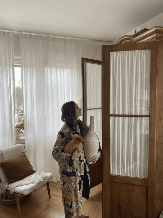 Une armoire en bois massif, stylisée avec des voiles blancs 