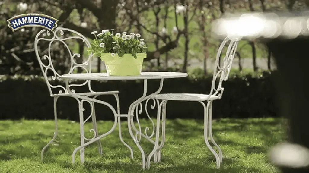 Un petit salon de jardin en fer forgé avec une peinture en bombe